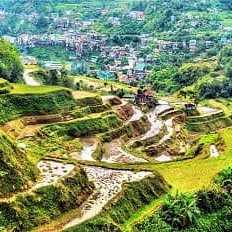 Blick auf die sattgrünen Reisterrassen von Banaue mit Dörfern im Hintergrund, Philippinen